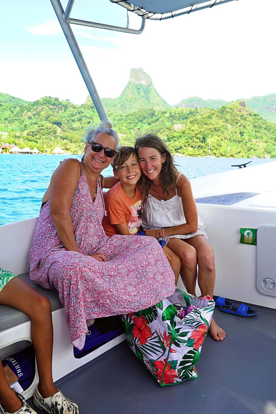 Guests smiling on a boat on the lagoon, with a jagged peak behind