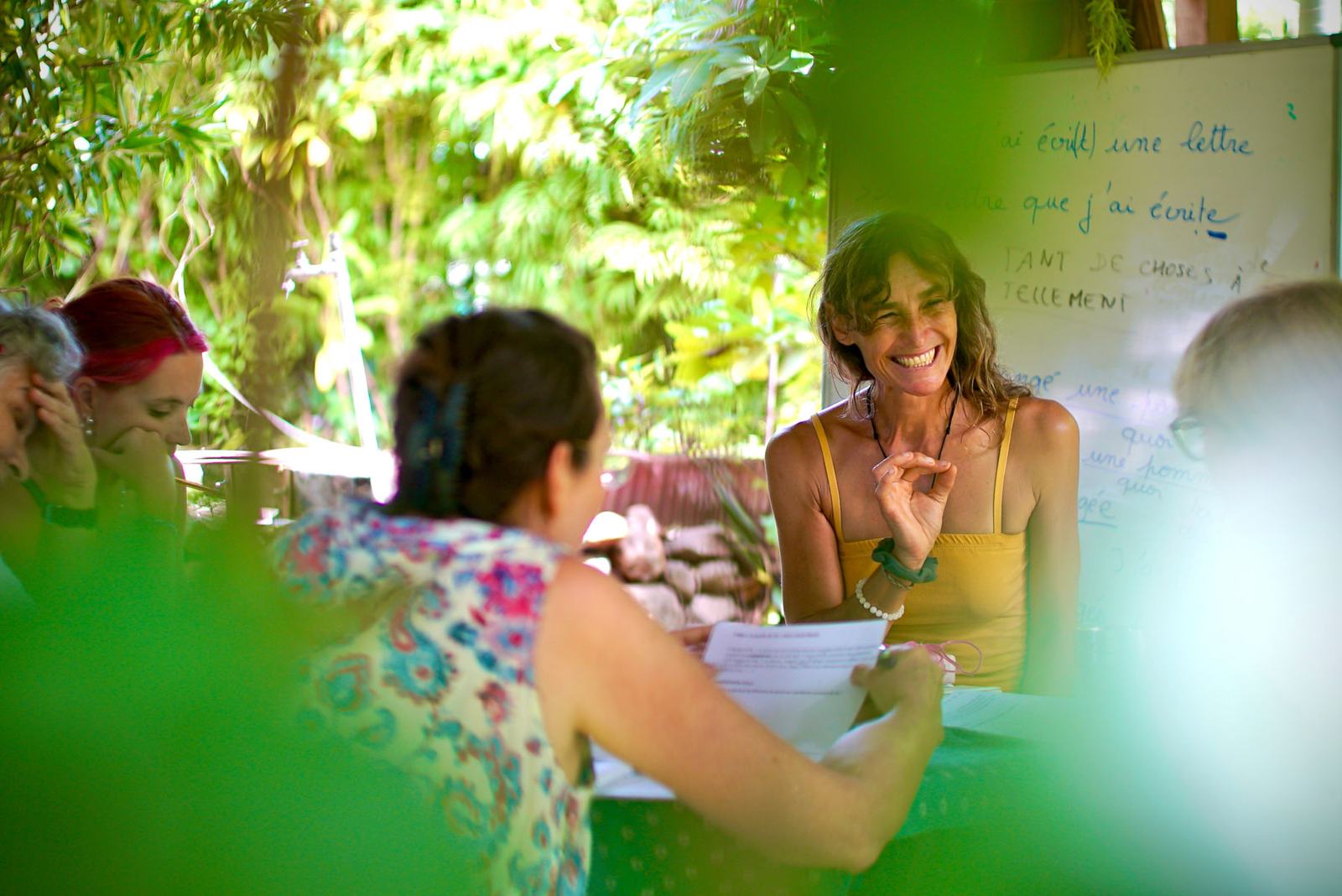 A teacher laughing with students at the garden table during a French class at Fare Om