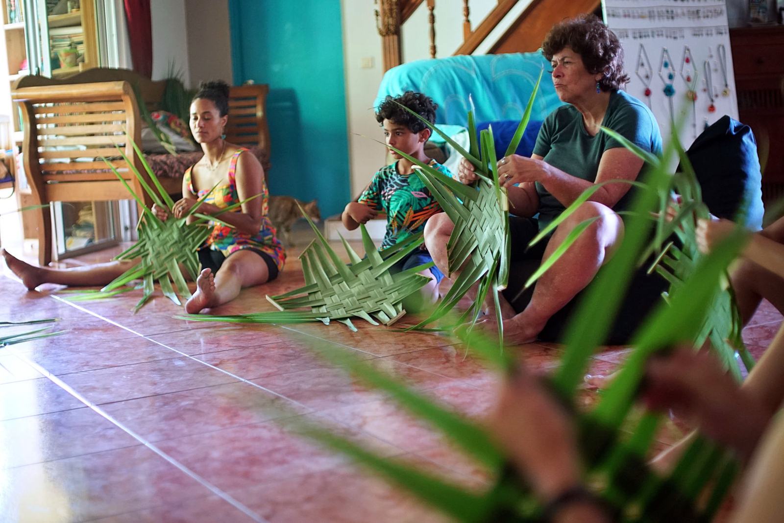 Guests weaving palm leaves on the floor at Fare Om