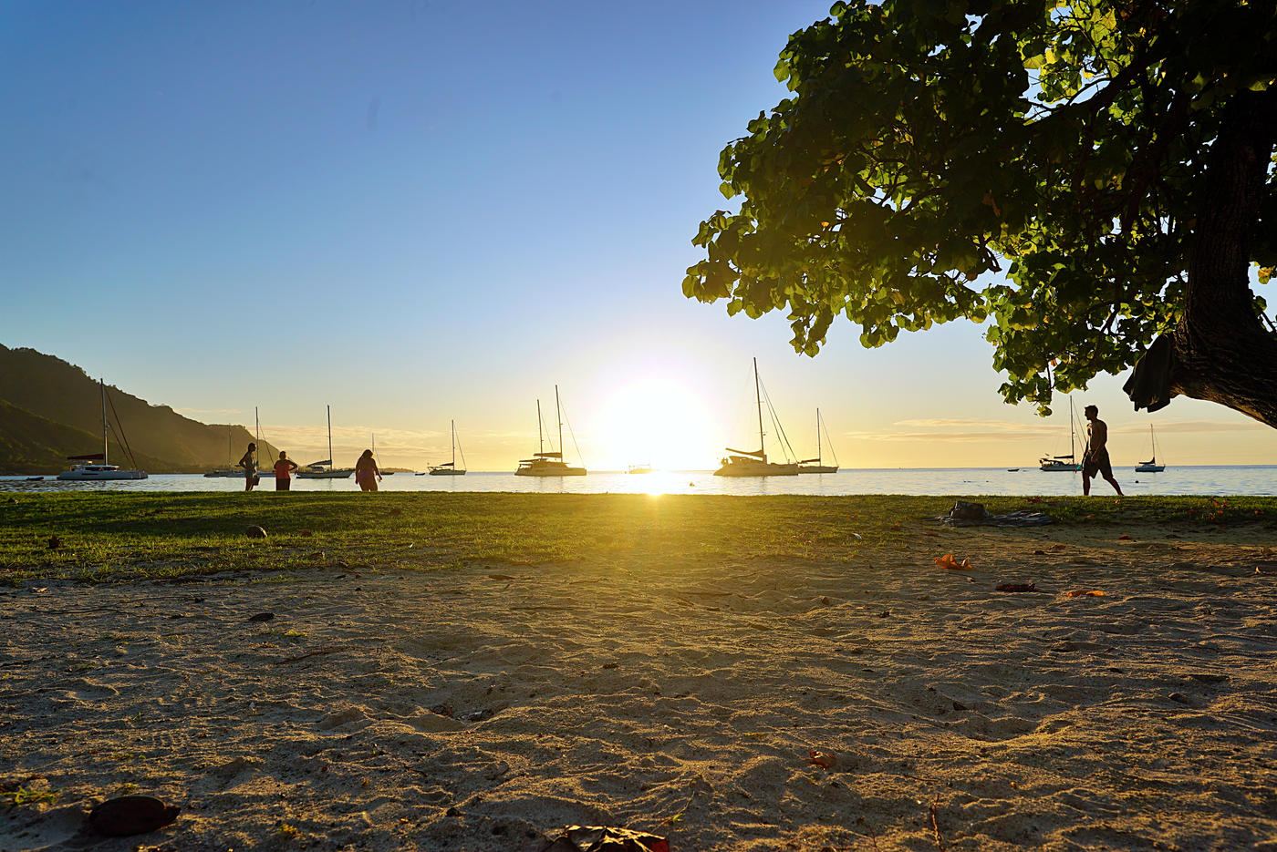Sunset over a beach with sailboats at anchor