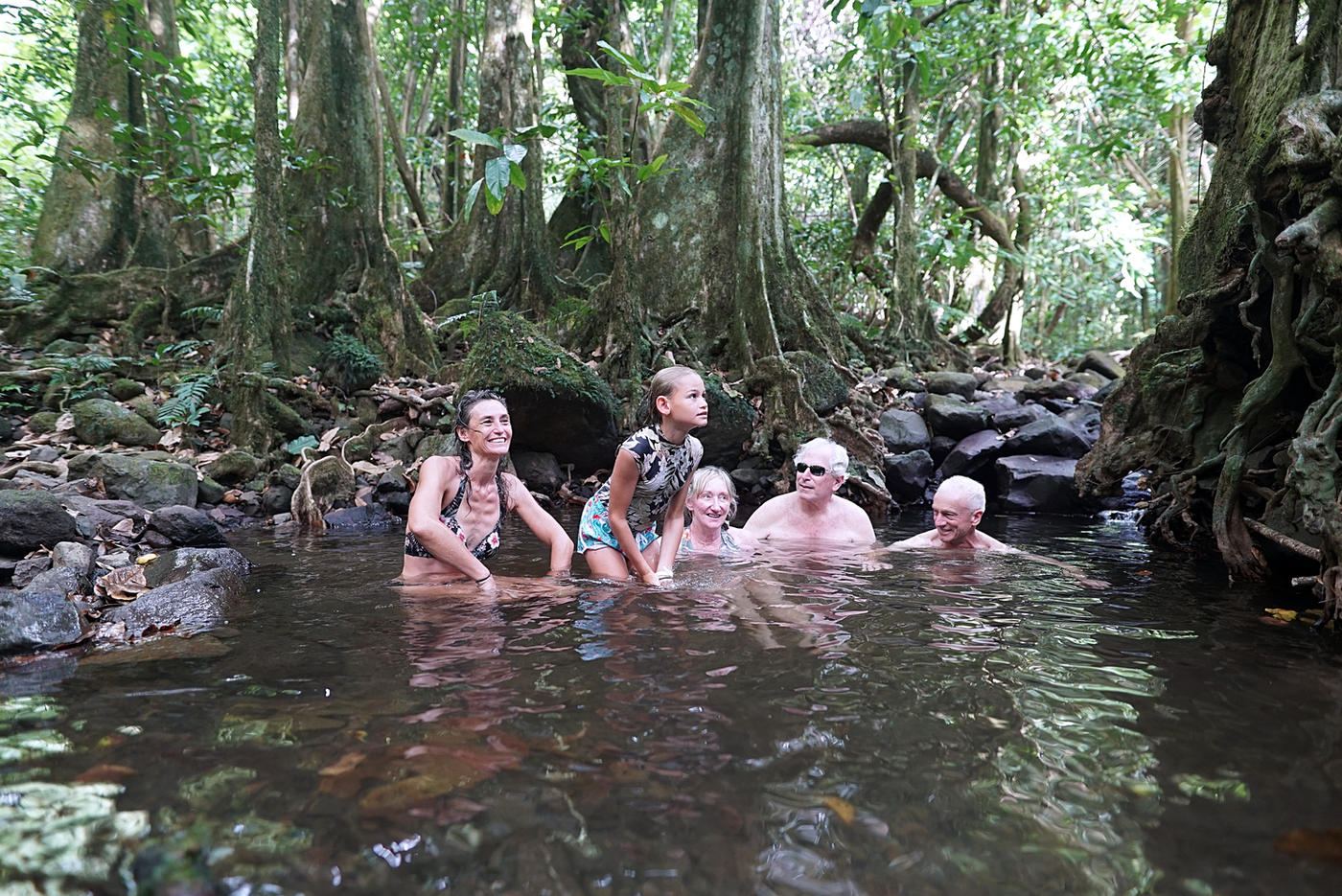 Guests cooling off in a forest pool below a waterfall